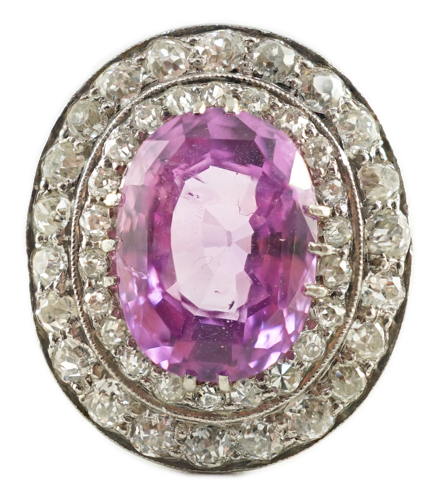 An early 20th century platinum, oval cut purple-pink sapphire and round cut diamond cluster set dress ring